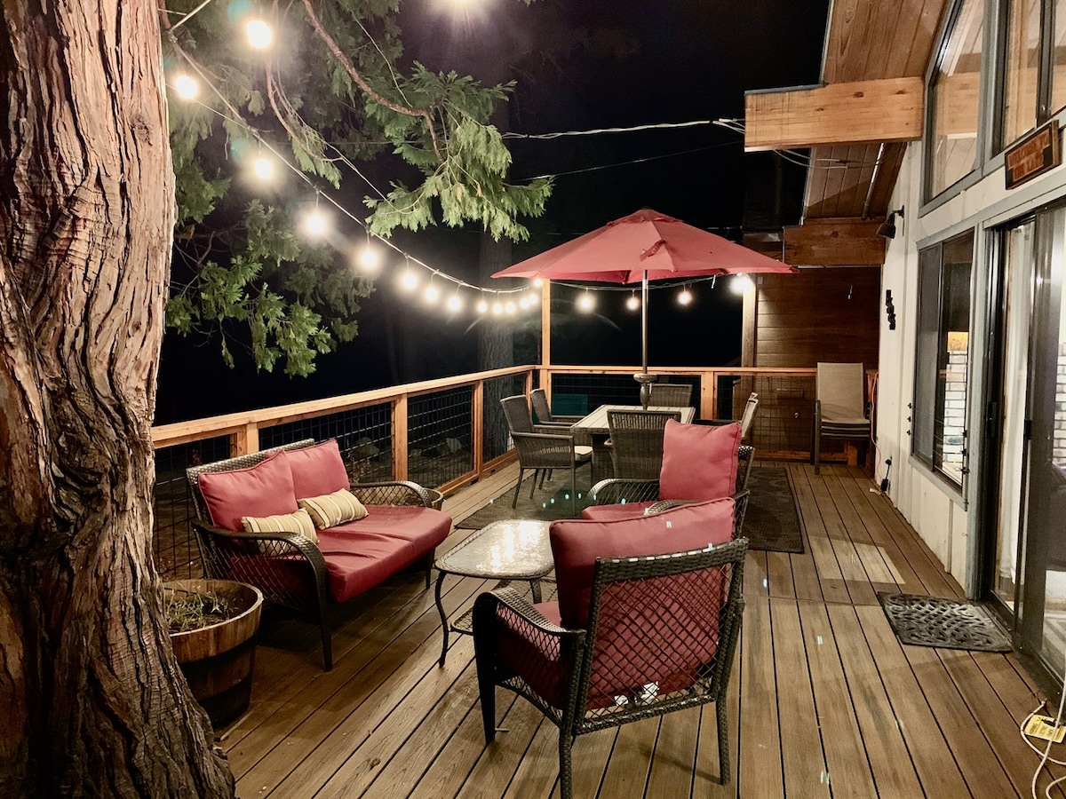 Evening deck seating under string lights, surrounded by Tahoe pines.