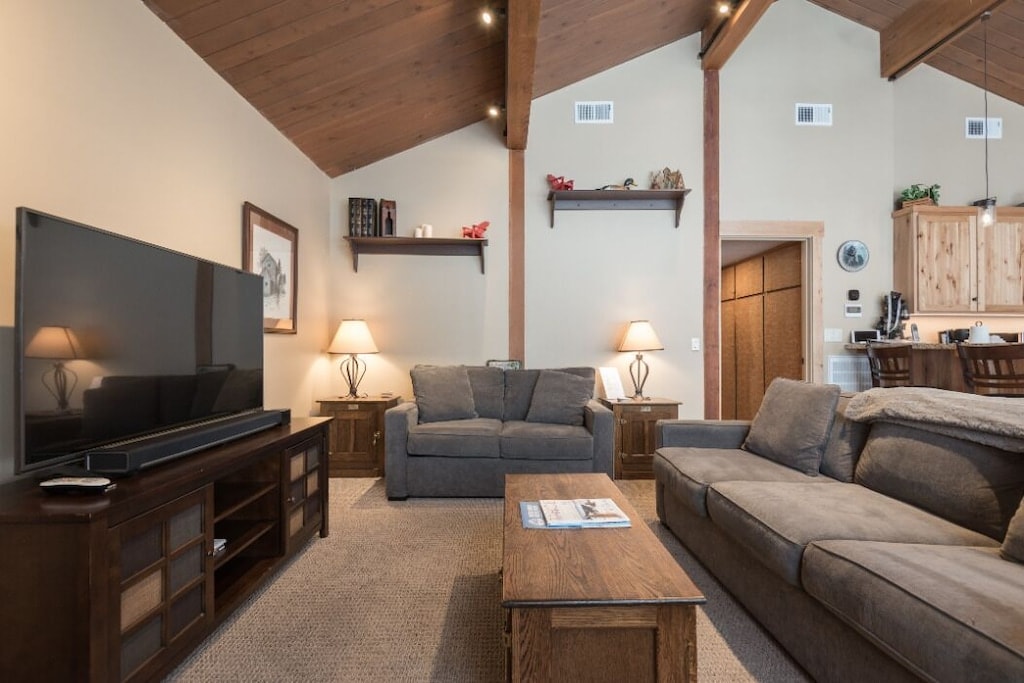 Cozy living room with large TV, vaulted ceiling, and comfortable sectional seating.
