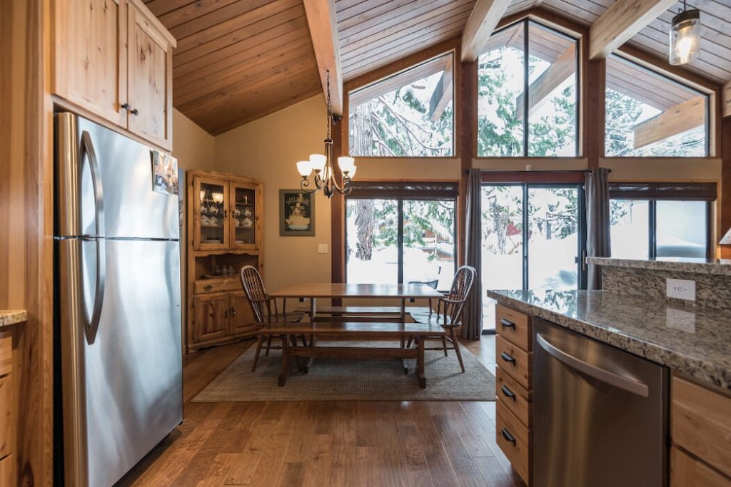 Dining nook framed by large windows and wooded views.