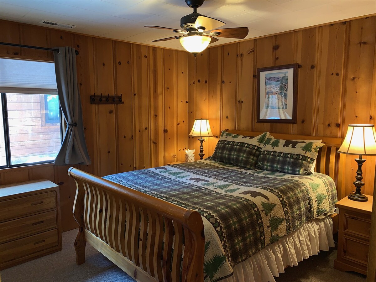 Back bedroom with queen bed, dresser, and natural light.