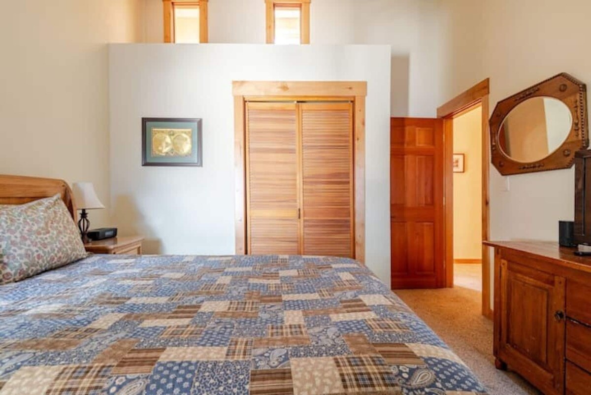 Front bedroom with queen bed, dresser, and mirror.