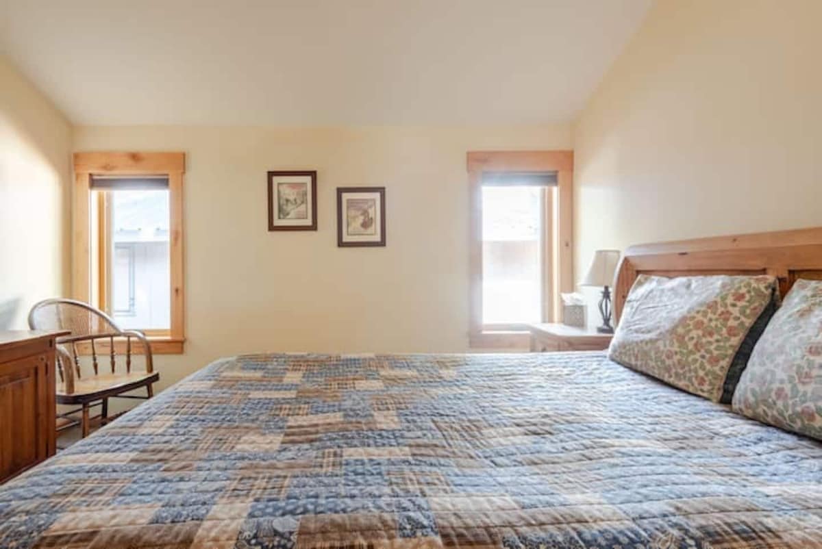 Front bedroom with queen bed and bright windows.