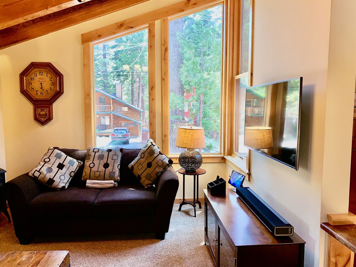Living room TV area with windows looking out to the trees.